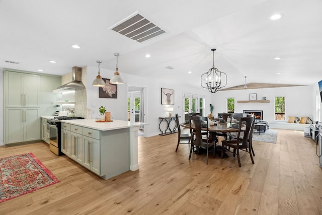 1803 Cedar Ridge Dr, Austin, TX 78741 - kitchen with range with gas stovetop, wall chimney range hood, a lit fireplace, light countertops, and vaulted ceiling