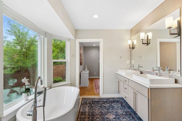 1803 Cedar Ridge Dr, Austin, TX 78741 - full bath with wood finished floors, a freestanding bath, double vanity, recessed lighting, and baseboards