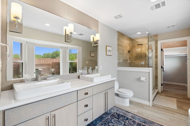 1803 Cedar Ridge Dr, Austin, TX 78741 - bathroom with wood finished floors, a stall shower, toilet, double vanity, and recessed lighting