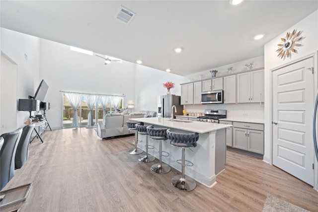 18005 Umberto Dr, Pflugerville, TX 78660 - kitchen with appliances with stainless steel finishes, a sink, a kitchen breakfast bar, open floor plan, and light wood-style flooring