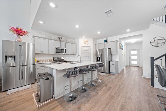18005 Umberto Dr, Pflugerville, TX 78660 - kitchen featuring stainless steel appliances, a kitchen breakfast bar, light wood-style flooring, light countertops, and recessed lighting