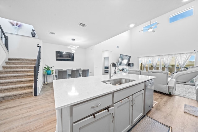 18005 Umberto Dr, Pflugerville, TX 78660 - kitchen with a sink, stainless steel dishwasher, light wood-style floors, light countertops, and a high ceiling