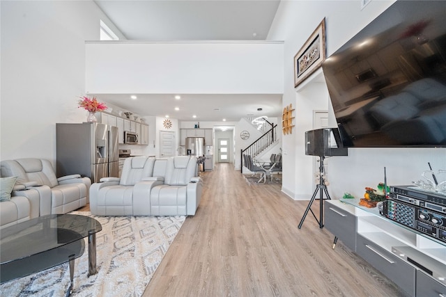 18005 Umberto Dr, Pflugerville, TX 78660 - living room with stairway, light wood-style flooring, a towering ceiling, and recessed lighting