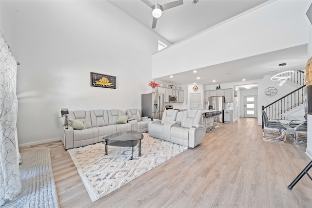 18005 Umberto Dr, Pflugerville, TX 78660 - living room featuring stairway, light wood finished floors, baseboards, a towering ceiling, and recessed lighting