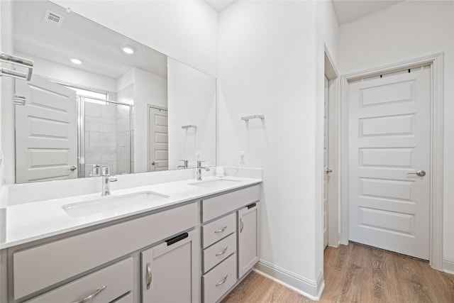 18005 Umberto Dr, Pflugerville, TX 78660 - bathroom featuring double vanity, wood finished floors, and a tile shower