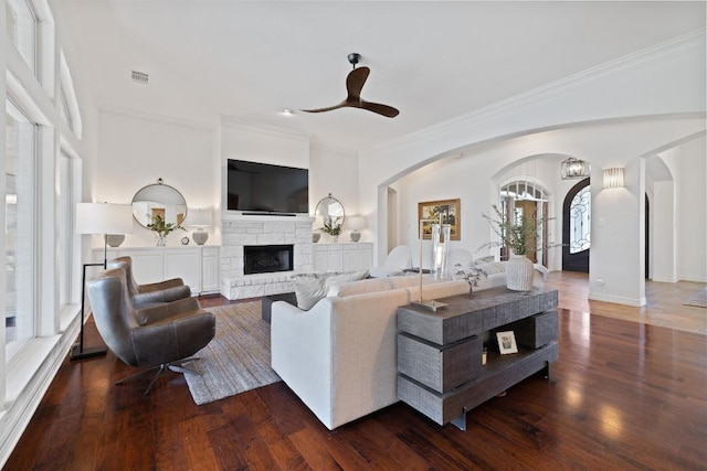 1310 Ventana Cyn, Leander, TX 78641 - living area with arched walkways, ornamental molding, dark wood-type flooring, a fireplace, and ceiling fan