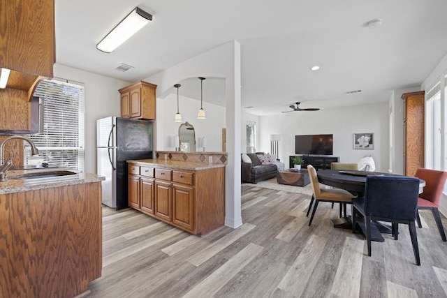 1310 Ventana Cyn, Leander, TX 78641 - kitchen featuring freestanding refrigerator, brown cabinetry, and light wood-style flooring