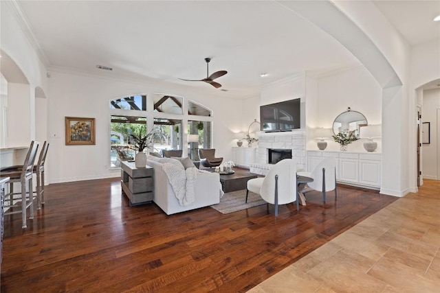 1310 Ventana Cyn, Leander, TX 78641 - living room with ceiling fan, arched walkways, a fireplace, ornamental molding, and wood finished floors
