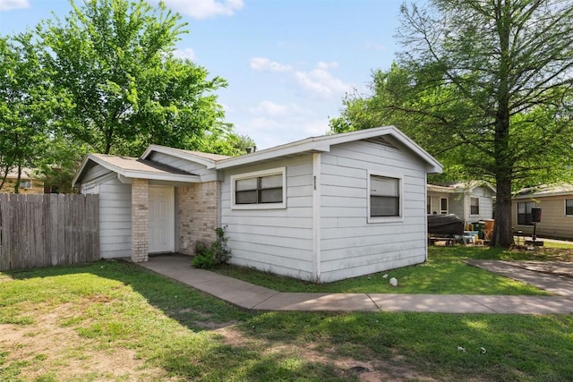 exterior space with brick siding, fence, and a front lawn