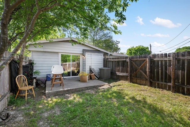 view of yard with an outbuilding, central AC, a fenced backyard, a patio, and a gate