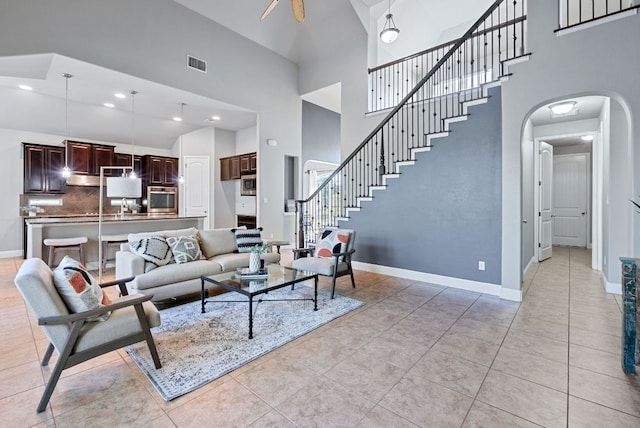 7817 Aria Loop, Austin, TX 78736 - living room featuring a high ceiling, arched walkways, baseboards, stairs, and light tile patterned floors