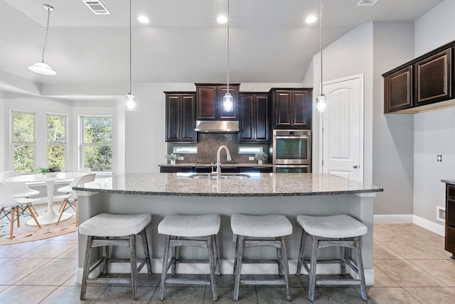 7817 Aria Loop, Austin, TX 78736 - kitchen featuring under cabinet range hood, lofted ceiling, a sink, double oven, and backsplash