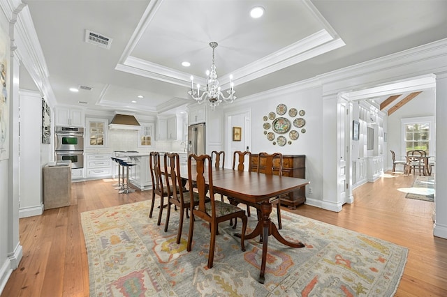 1307 Elton Ln, Austin, TX 78703 - dining room with light wood-type flooring, a chandelier, a raised ceiling, and ornamental molding