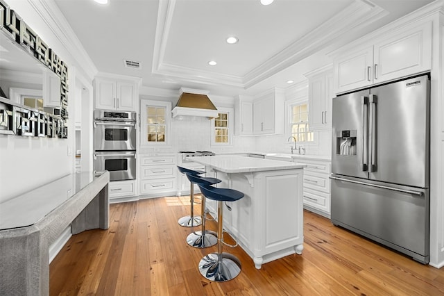 1307 Elton Ln, Austin, TX 78703 - kitchen with appliances with stainless steel finishes, custom exhaust hood, a raised ceiling, white cabinets, and recessed lighting