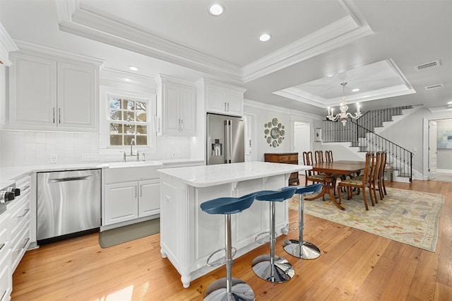1307 Elton Ln, Austin, TX 78703 - kitchen featuring stainless steel appliances, a raised ceiling, tasteful backsplash, white cabinets, and light wood-style floors