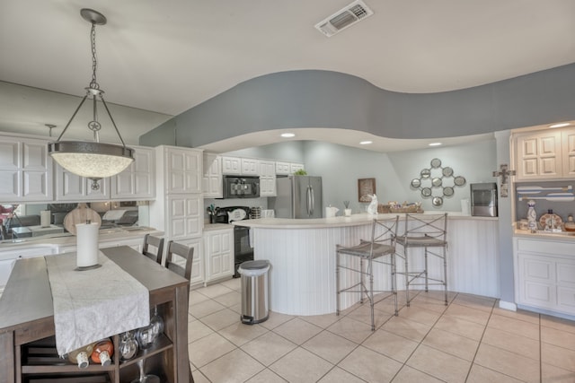 605 Port Unit 3, Horseshoe Bay, TX 78657 - kitchen with freestanding refrigerator, black microwave, a peninsula, light tile patterned floors, and a kitchen bar