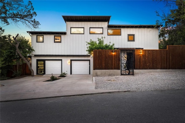 view of front of property featuring an attached garage, board and batten siding, concrete driveway, and fence