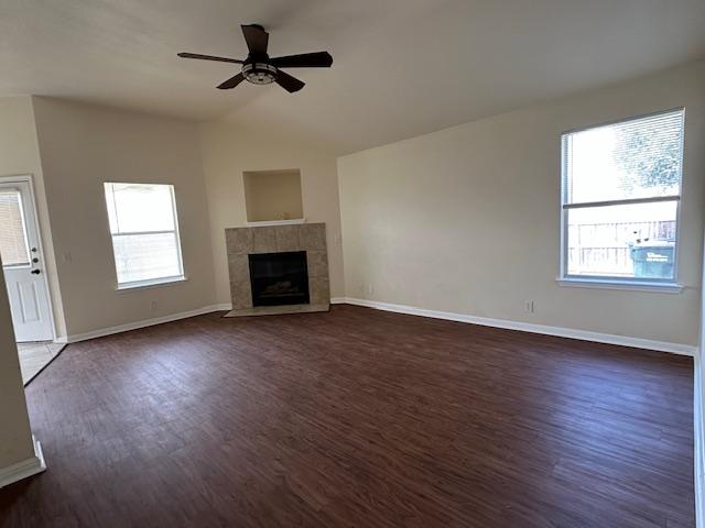 377 Donatello, Kyle, TX 78640 - unfurnished living room with dark wood finished floors, a ceiling fan, vaulted ceiling, and a tiled fireplace
