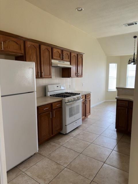 377 Donatello, Kyle, TX 78640 - kitchen with white appliances, vaulted ceiling, tasteful backsplash, under cabinet range hood, and light tile patterned flooring