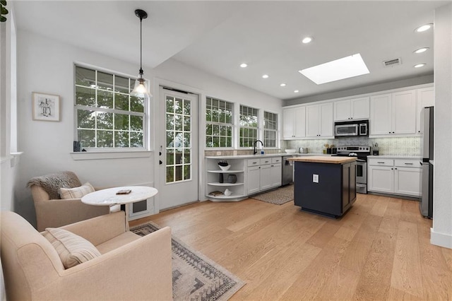 5224 Mccormick Mountain Dr, Austin, TX 78734 - kitchen featuring appliances with stainless steel finishes, a skylight, white cabinetry, a center island, and light wood-style flooring