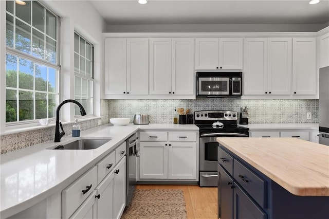 5224 Mccormick Mountain Dr, Austin, TX 78734 - kitchen with stainless steel appliances, a sink, white cabinets, light wood-style flooring, and recessed lighting