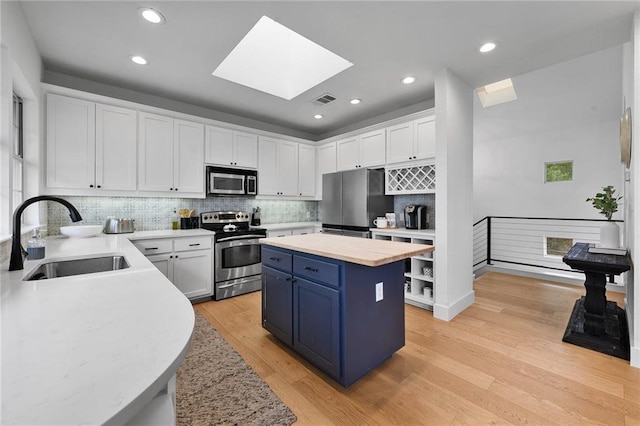 5224 Mccormick Mountain Dr, Austin, TX 78734 - kitchen featuring stainless steel appliances, a sink, blue cabinets, white cabinets, and a skylight