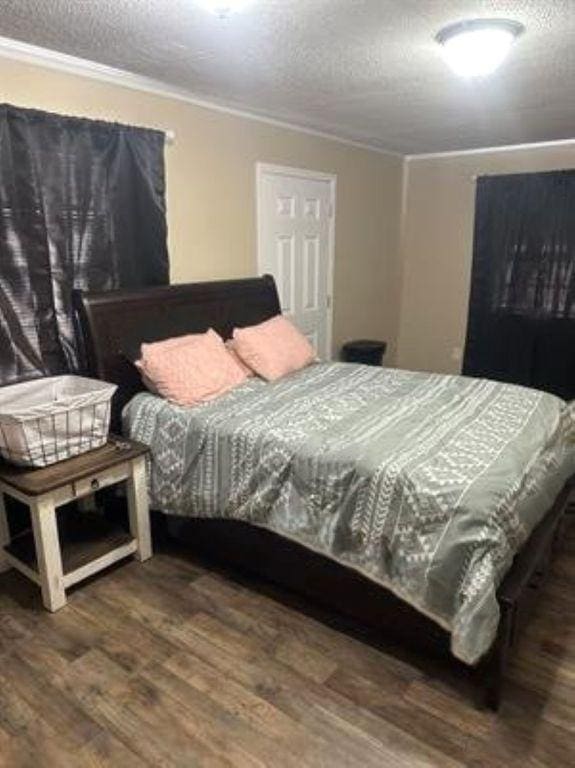 bedroom featuring crown molding, wood finished floors, and a textured ceiling