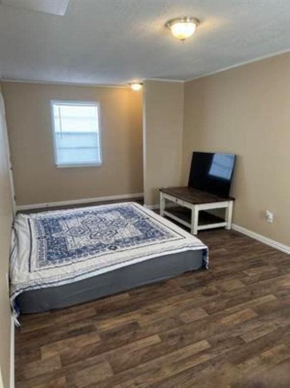 bedroom with baseboards, crown molding, and wood finished floors