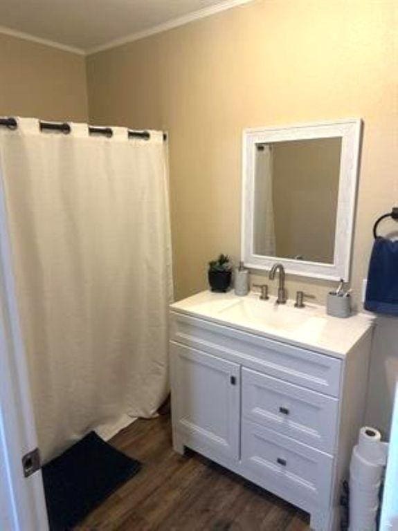 full bathroom with crown molding, wood finished floors, and vanity