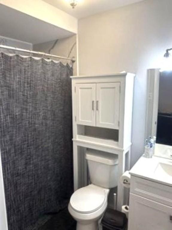 bathroom with toilet, a shower with shower curtain, and vanity