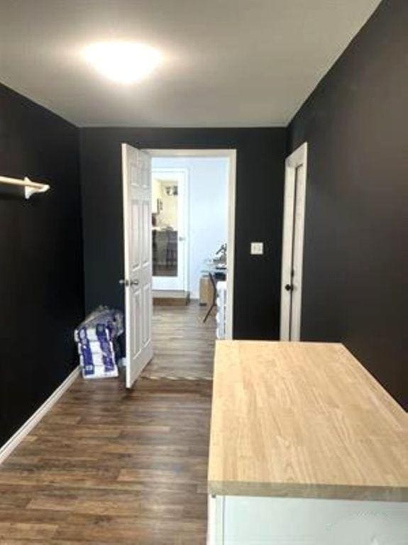 hall with dark wood-style flooring and baseboards