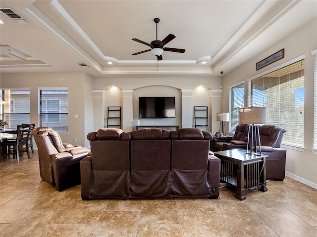living area featuring ornamental molding, visible vents, a raised ceiling, decorative columns, and ceiling fan