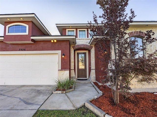 view of front of property with concrete driveway, stucco siding, stone siding, and a garage