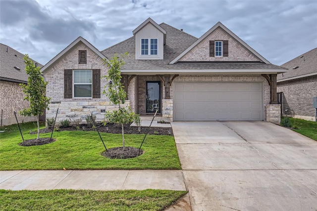 299 Grand Teton Dr, Kyle, TX 78640 - view of front of home with stone siding, roof with shingles, concrete driveway, a front lawn, and an attached garage