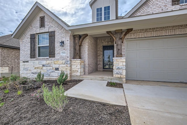 299 Grand Teton Dr, Kyle, TX 78640 - view of exterior entry with a porch, concrete driveway, stone siding, and brick siding