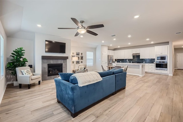 299 Grand Teton Dr, Kyle, TX 78640 - living room with light wood-style flooring, ceiling fan, a tile fireplace, recessed lighting, and baseboards