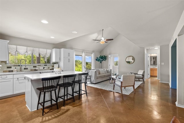 437 Venture Blvd S, Point Venture, TX 78645 - kitchen with light countertops, a center island, a kitchen breakfast bar, white cabinets, and plenty of natural light