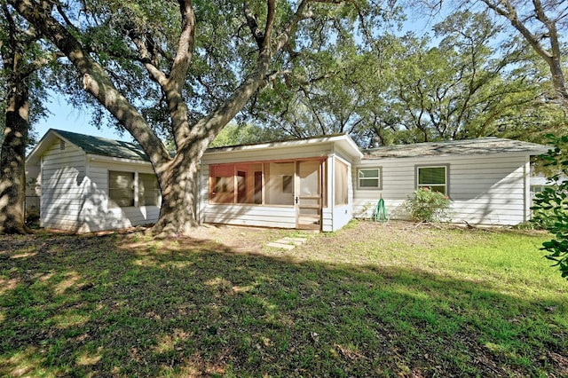 back of property featuring a sunroom and a lawn
