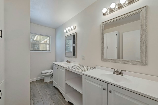 bathroom with double vanity, baseboards, a sink, and toilet