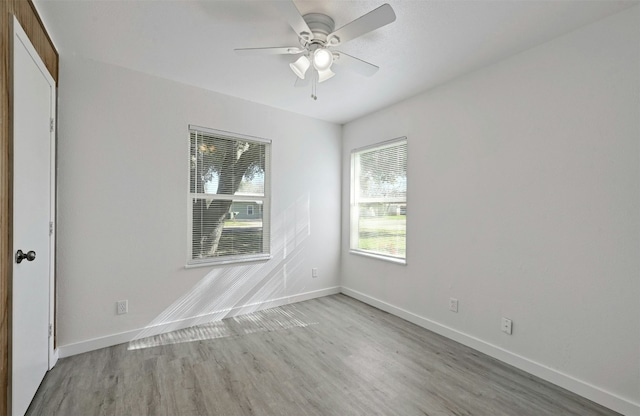 spare room featuring baseboards, light wood-type flooring, and ceiling fan