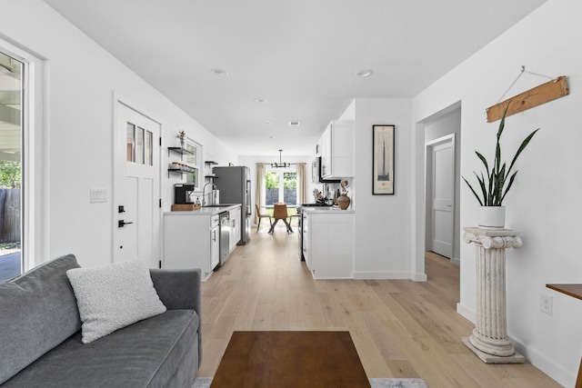living area with recessed lighting, baseboards, a notable chandelier, and light wood-type flooring