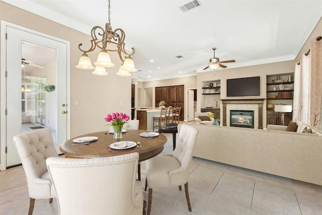 316 Trail Of The Flowers, Georgetown, TX 78633 - dining area featuring a ceiling fan, a tile fireplace, ornamental molding, light tile patterned floors, and built in shelves