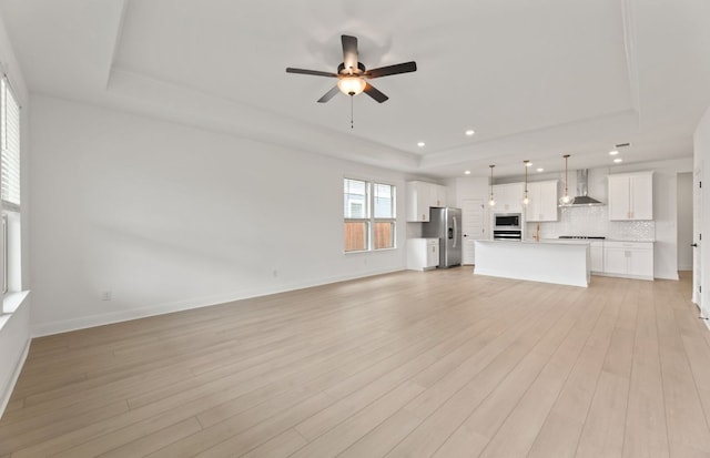 329 Singing Dove Way, Liberty Hill, TX 78642 - unfurnished living room with a raised ceiling, recessed lighting, ceiling fan, and light wood-style flooring