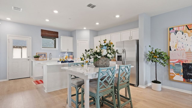 2634 Caleb Asher Loop, Round Rock, TX 78665 - kitchen featuring white cabinets, visible vents, light wood-style flooring, and stainless steel fridge with ice dispenser