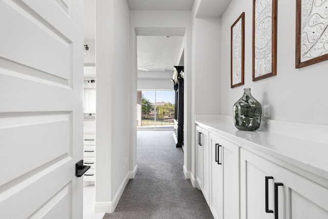 corridor with dark carpet and baseboards