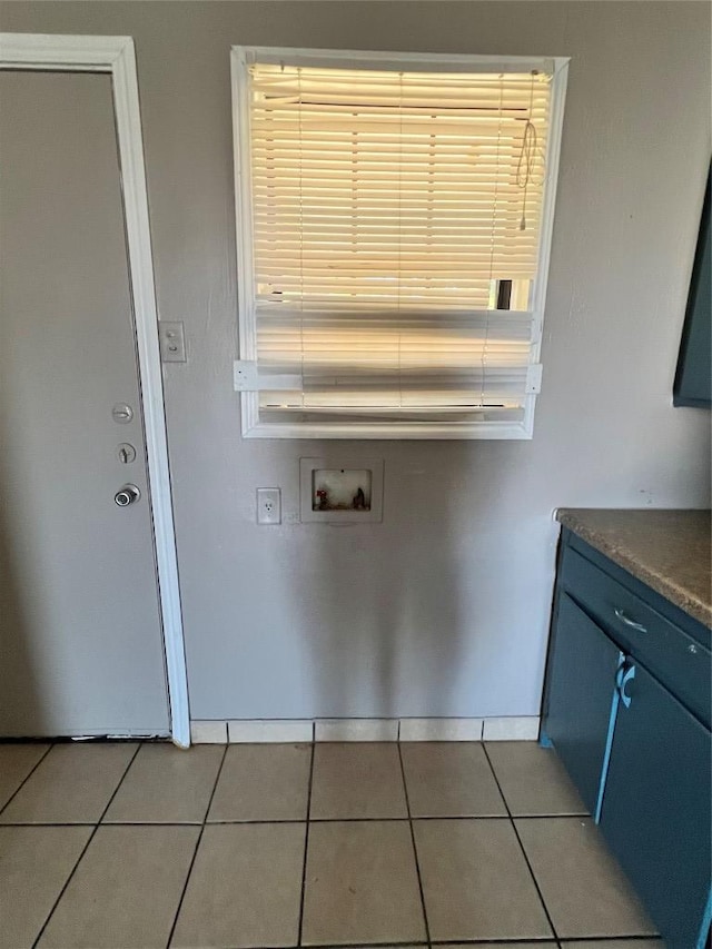 laundry room with light tile patterned flooring, laundry area, washer hookup, and baseboards