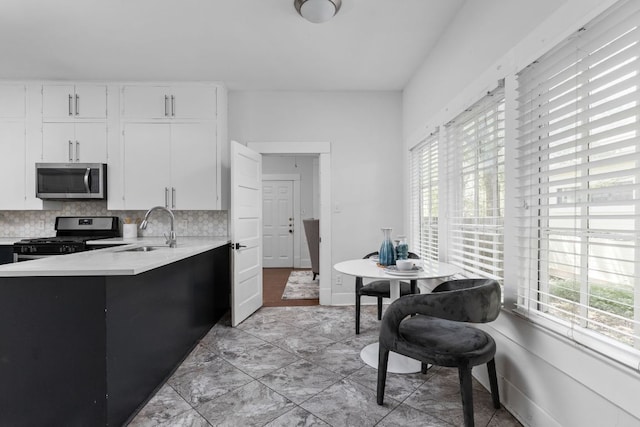207 W 39th St, Austin, TX 78751 - kitchen with stainless steel appliances, light countertops, backsplash, white cabinets, and a peninsula