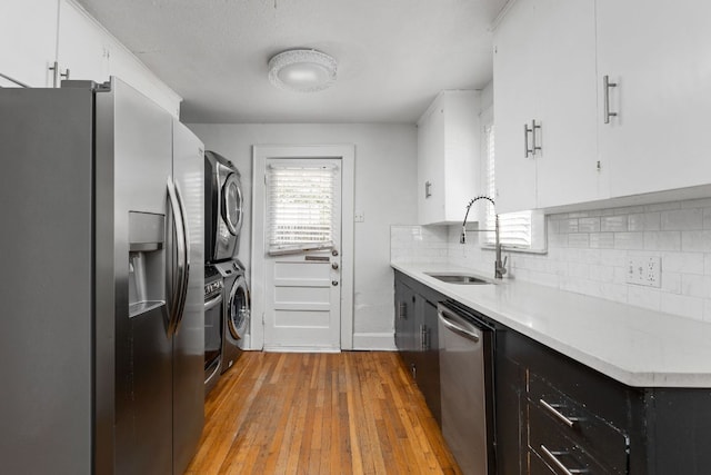 207 W 39th St, Austin, TX 78751 - kitchen featuring stainless steel appliances, estacked washer and dryer, light wood-style floors, light countertops, and white cabinets