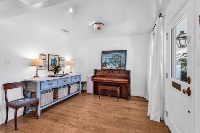 living area with baseboards, wood finished floors, and visible vents