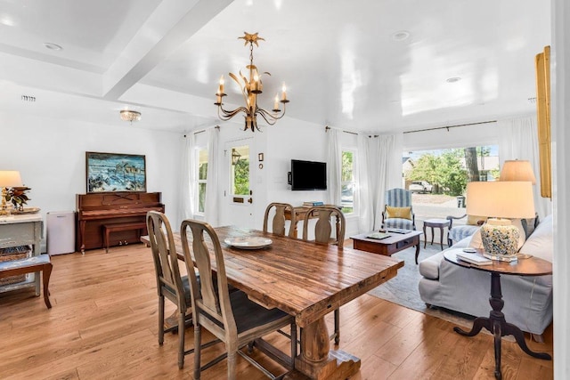 dining space with an inviting chandelier, beamed ceiling, light wood finished floors, and visible vents